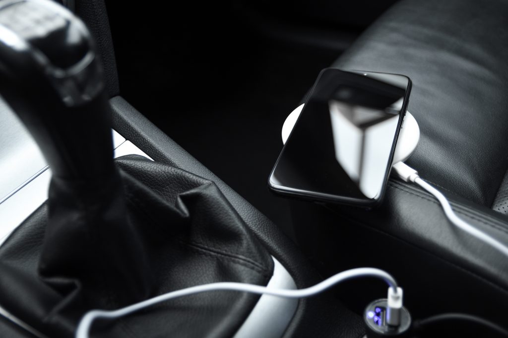 Telefon na ładowarce indukcyjnej podłączonej do gniazdka zapalniczki w samochodzie